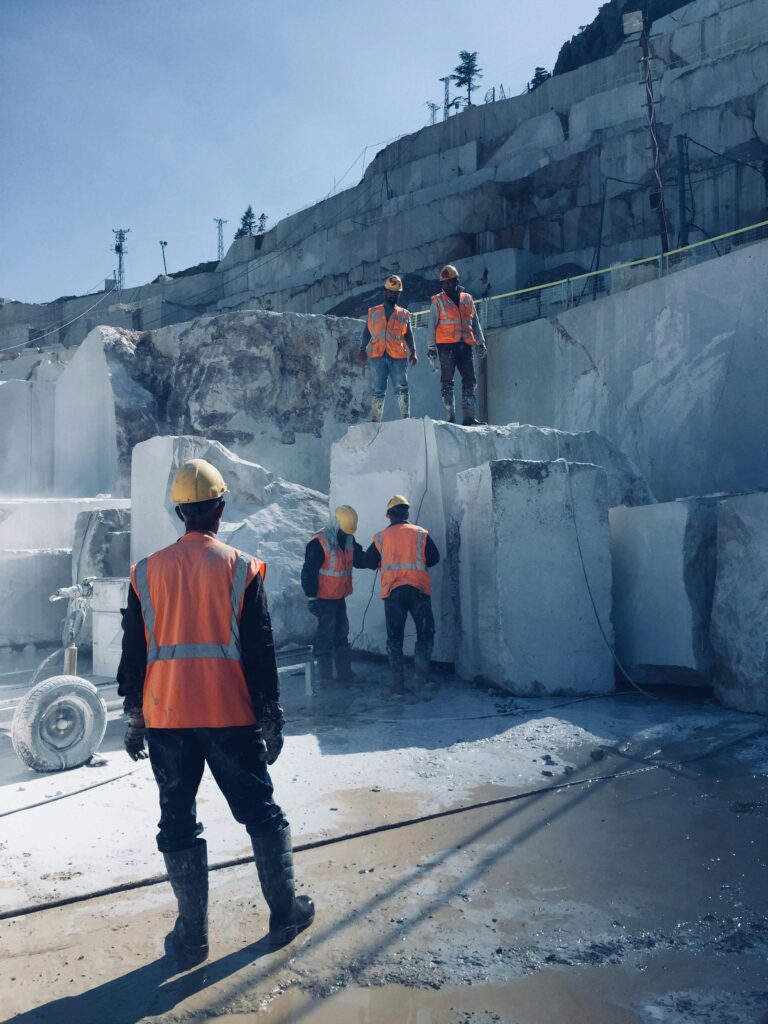 Construction workers with helmets and vests at a marble quarry site in Turkey.
